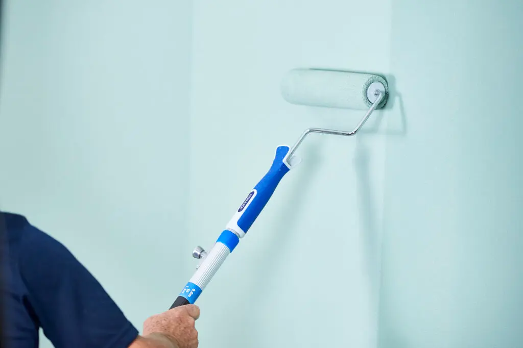 Pintor profesional aplicando esmalte de alta gama en pared interior de villa en Marbella